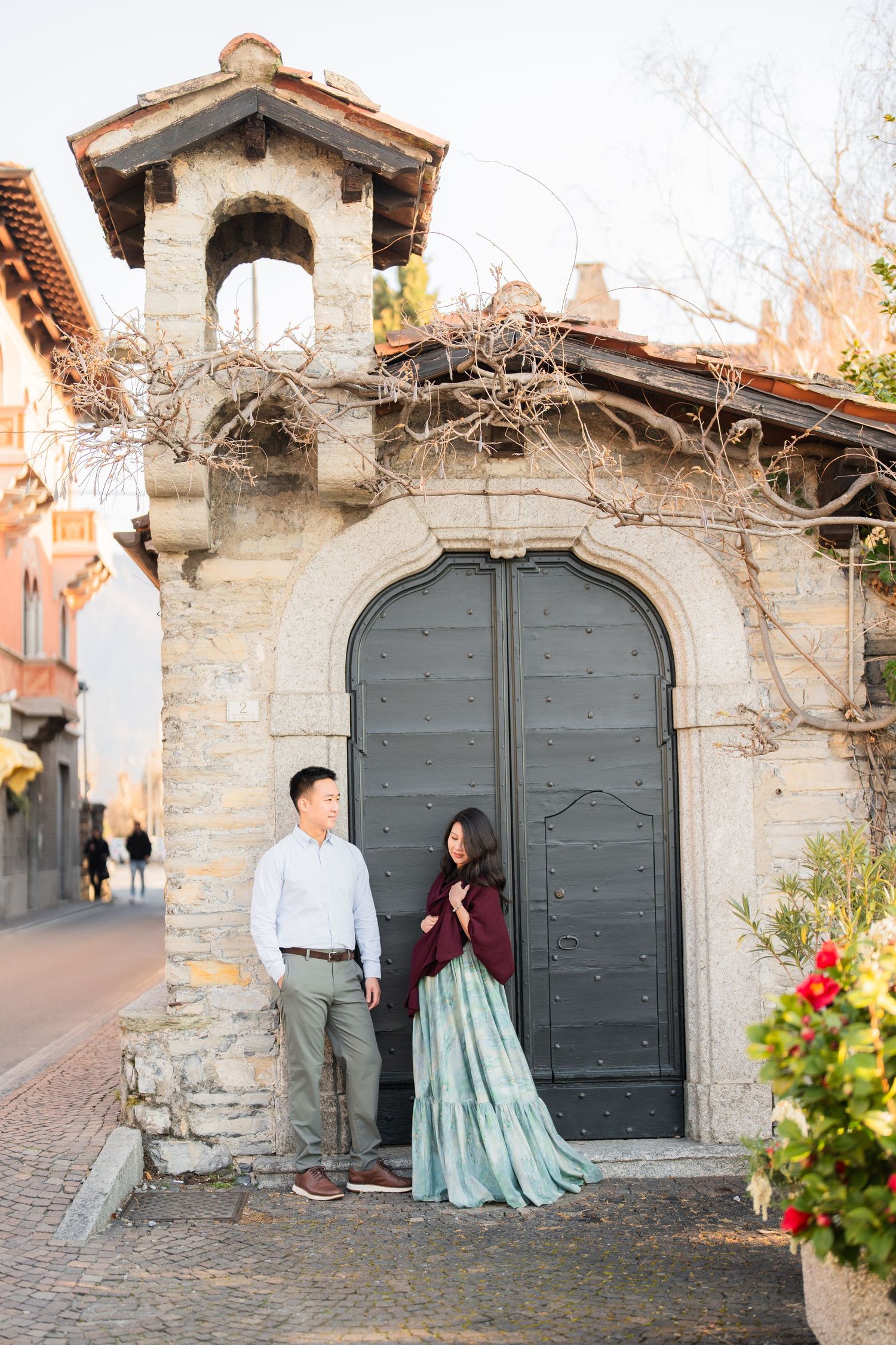 Couple posing in front of a historic stone archway door on a charming European cobblestone street.