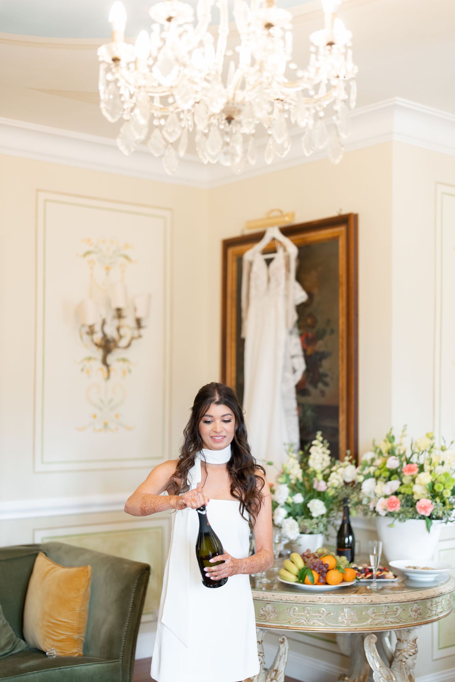 Elegant room with crystal chandelier, vintage furniture, and floral arrangements on a round table.