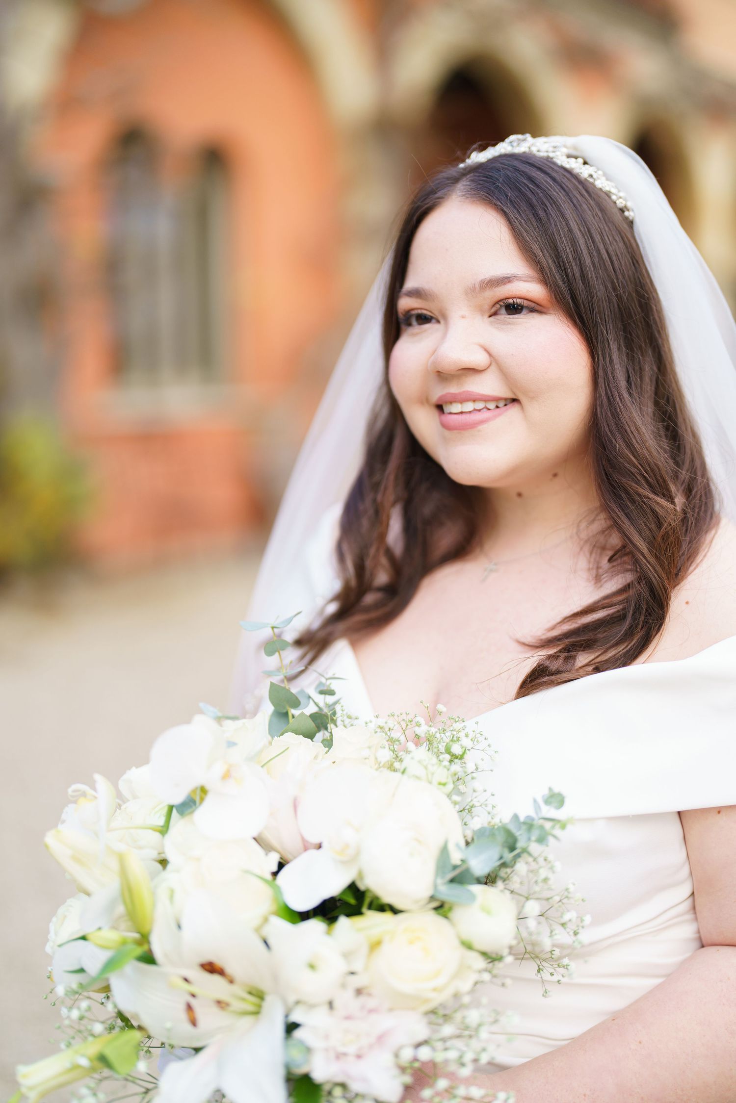 A white lace wedding dress with delicate floral bouquet in natural light.