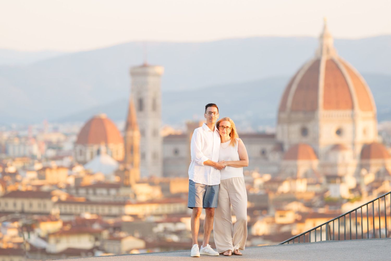 Couple admiring the stunning Florence skyline with Duomo cathedral and historic architecture at sunset.