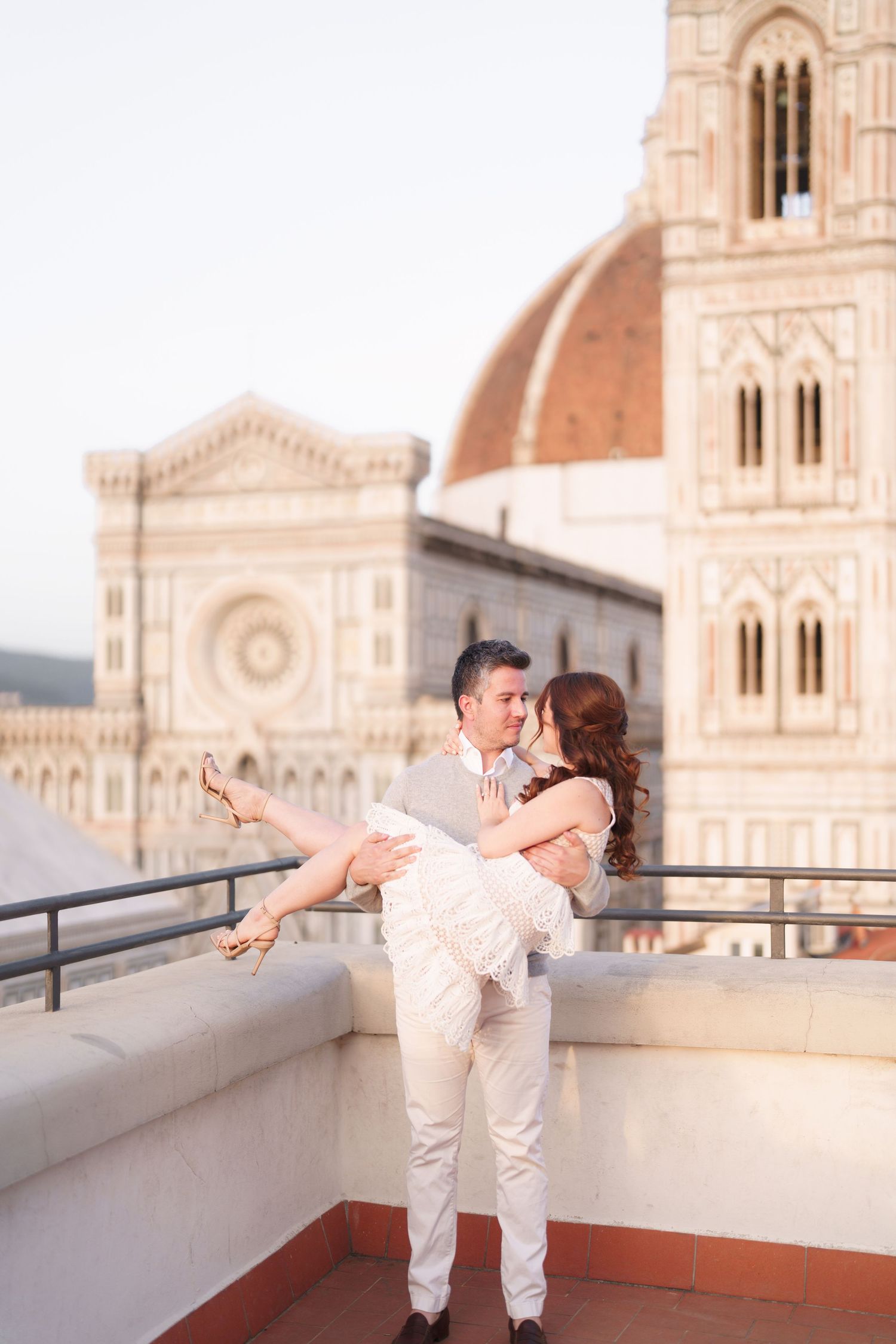 A couple shares a romantic moment on a rooftop terrace overlooking Florence Cathedral during sunset.