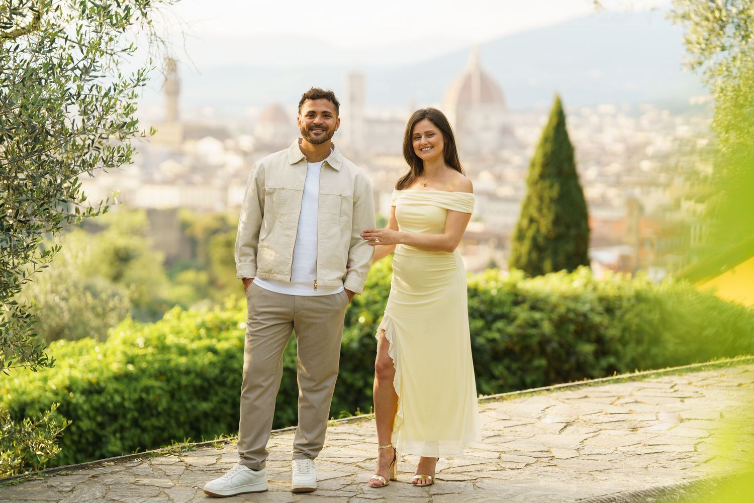 Couple posing together in Florence, Italy with the Duomo cathedral and cityscape in the background.