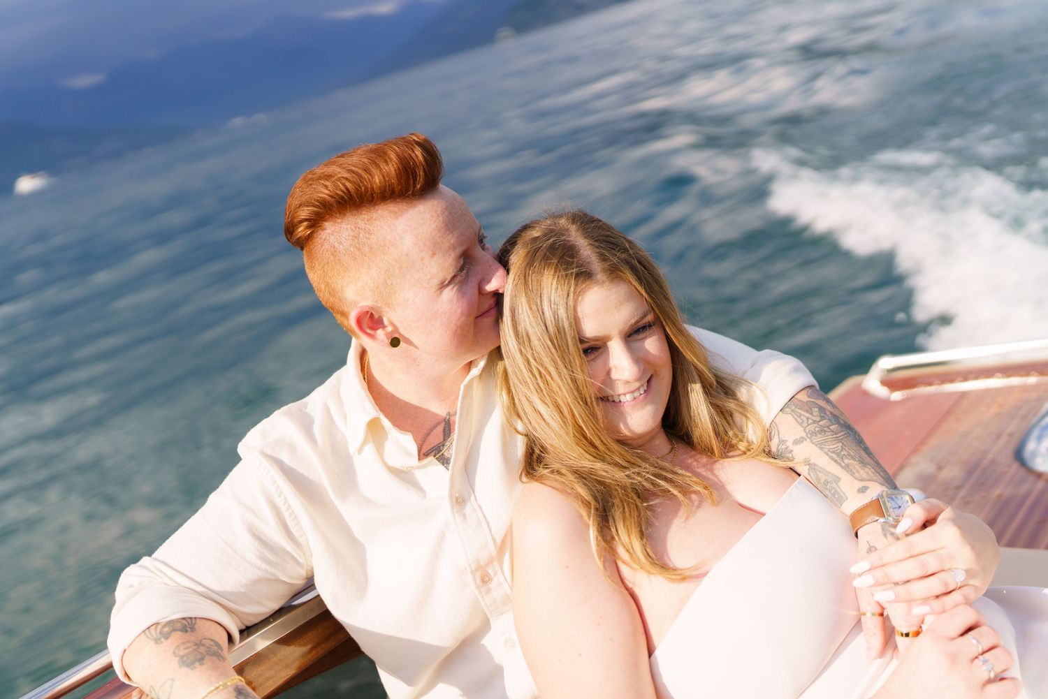 Couple sharing a romantic moment on a wooden boat with blue water in the background.