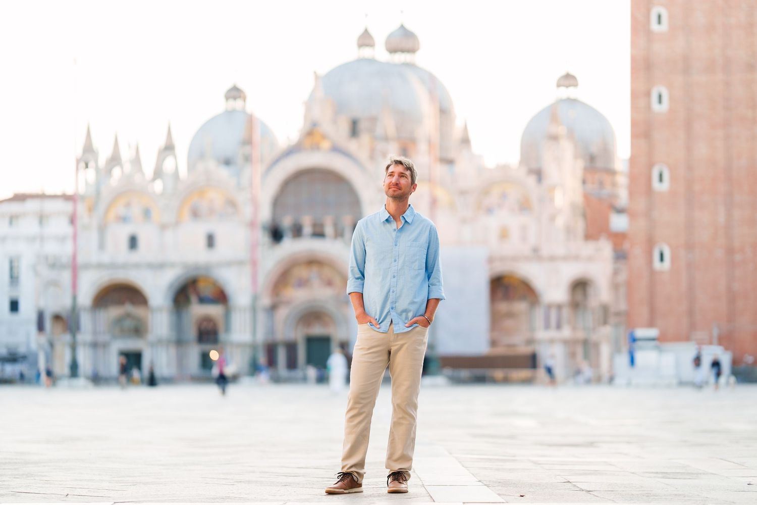 Man standing in St. Mark's Square, Venice, with the iconic Basilica di San Marco in the background.