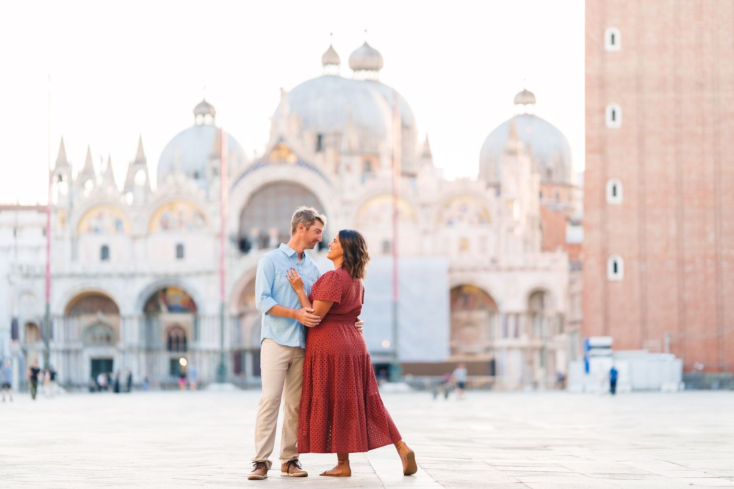 Couple sharing a romantic kiss in St. Mark's Square, Venice, with the iconic Basilica di San Marco in the background.