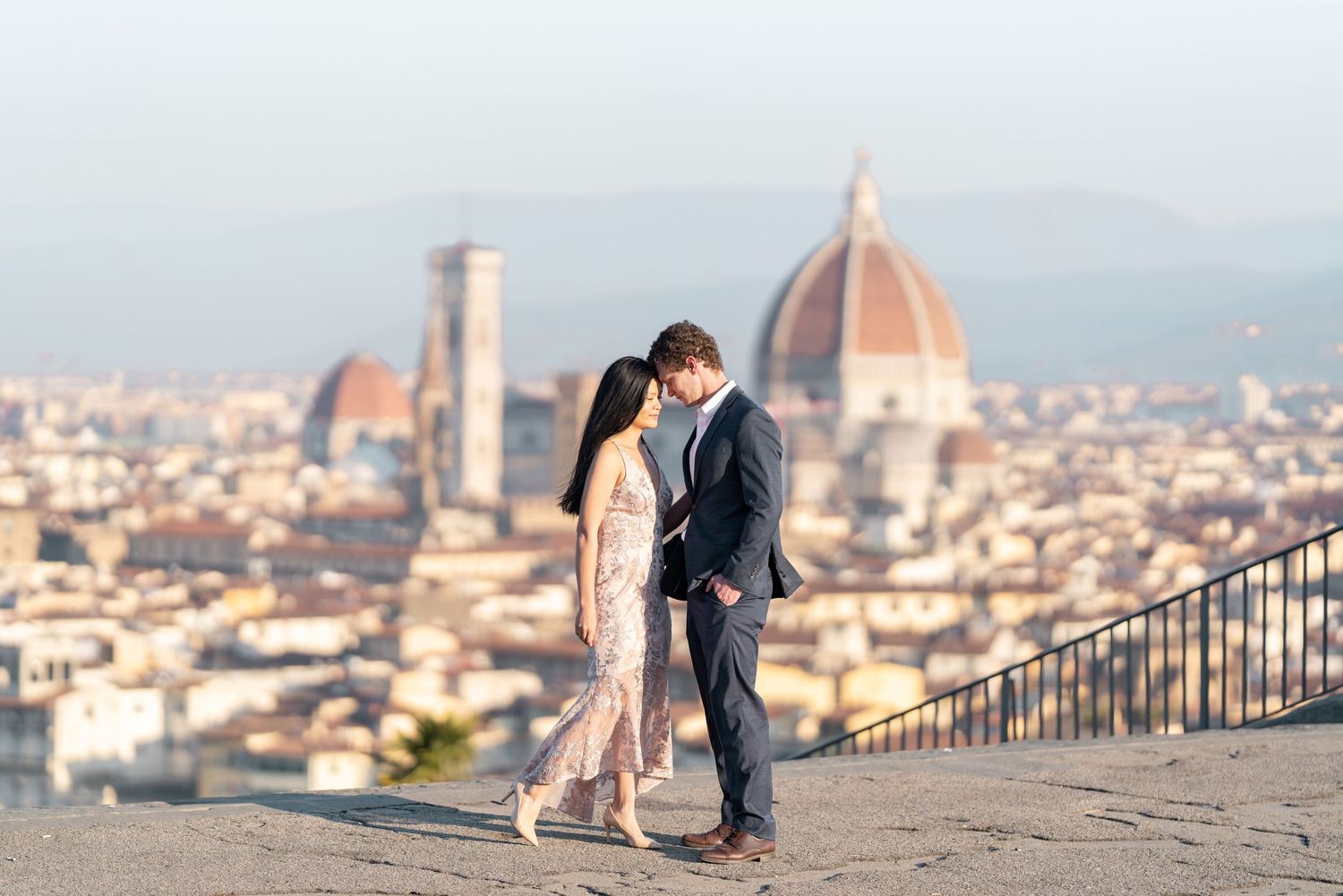 A couple shares a romantic moment overlooking the beautiful cityscape of Florence, Italy with its iconic Duomo cathedral.