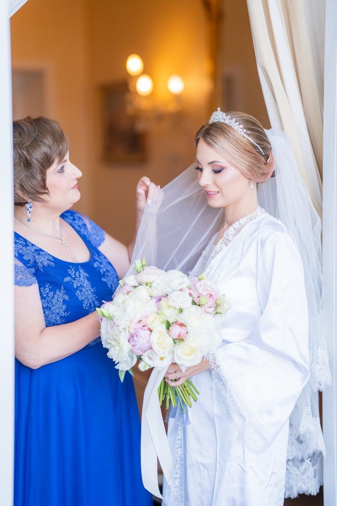 Wedding preparation scene with white and blue attire and a bouquet of pink and white flowers.