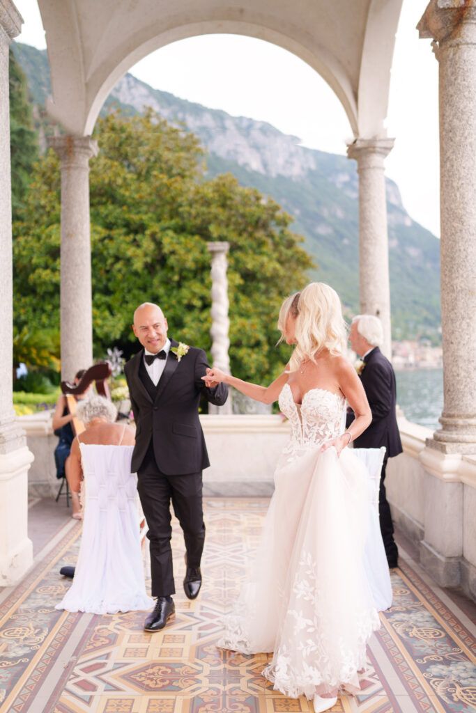 Wedding party dances through elegant columned terrace with mountain views.