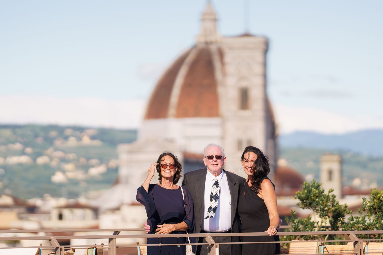 Group enjoying sunset views from Florence rooftop terrace with Duomo backdrop.