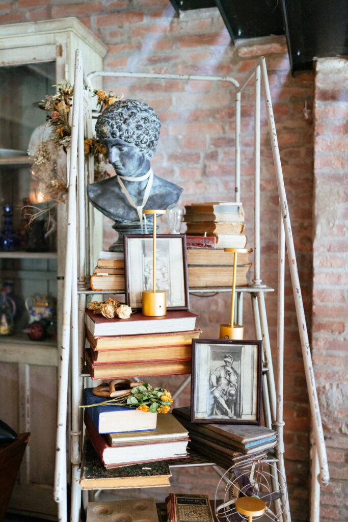 Rustic wedding decor featuring stacked books, candles and vintage items against exposed brick walls.