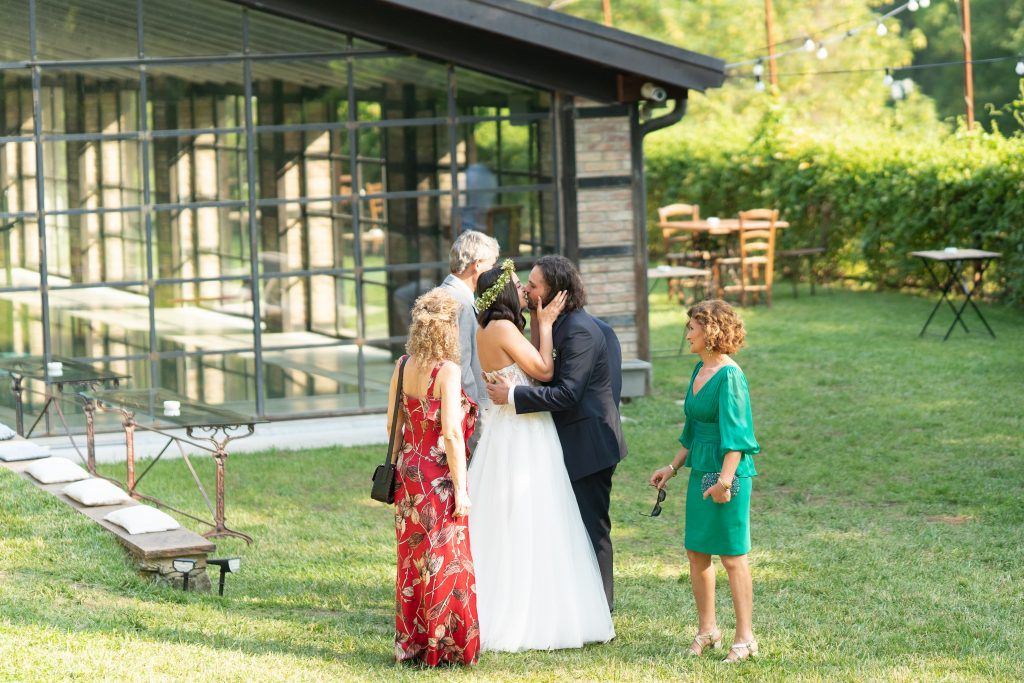 Wedding guests socializing on manicured lawn outside modern glass venue.