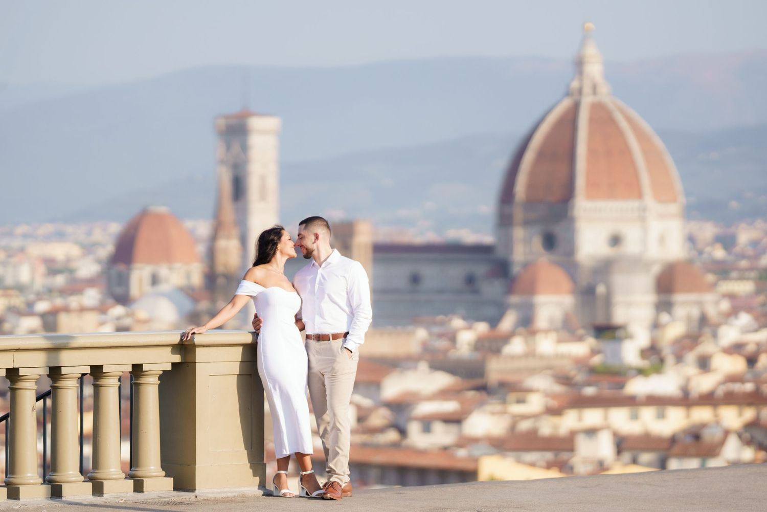 Couple enjoying panoramic views of Florence's iconic Duomo cathedral and historic cityscape from Piazzale Michelangelo viewpoint.