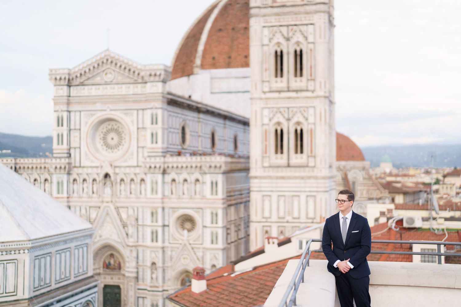 Panoramic view of Florence Cathedral and cityscape with terracotta rooftops against a cloudy sky in Italy.
