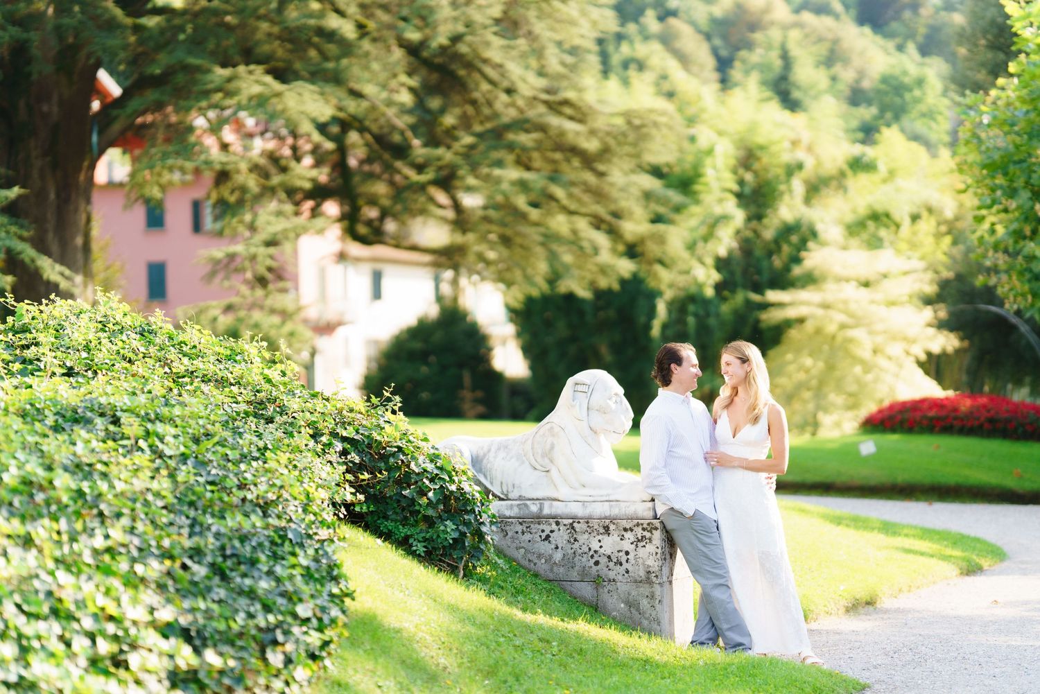 A scenic outdoor garden wedding ceremony setup with white chairs arranged in rows on a lush green lawn.