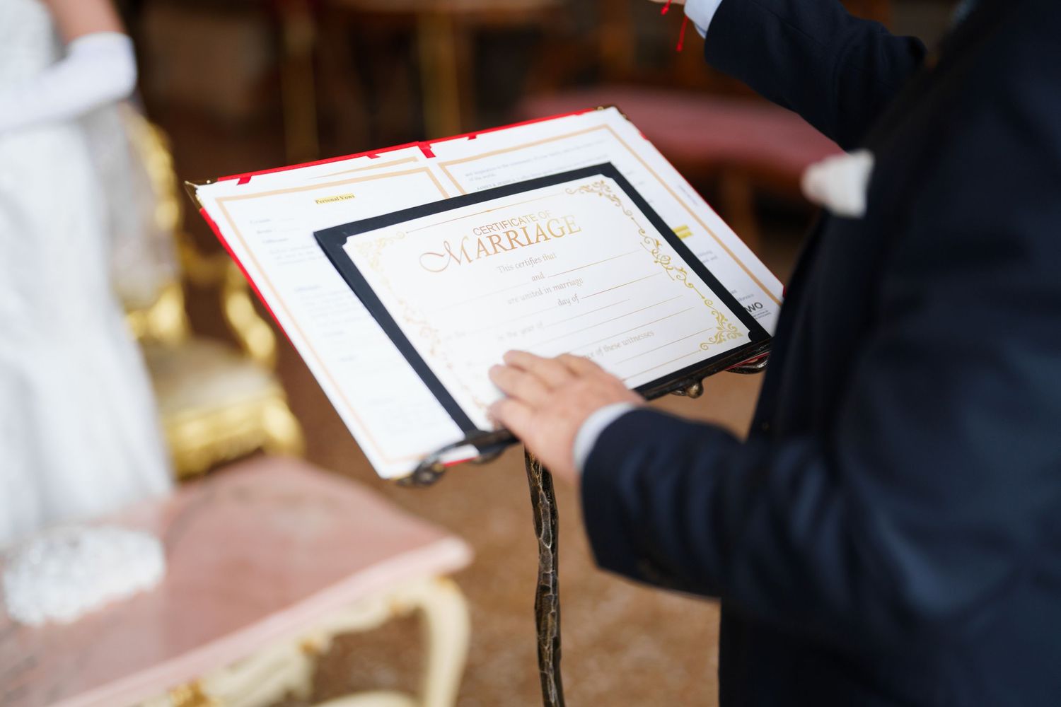 Person in business attire holds paperwork while seated at a desk during a meeting.