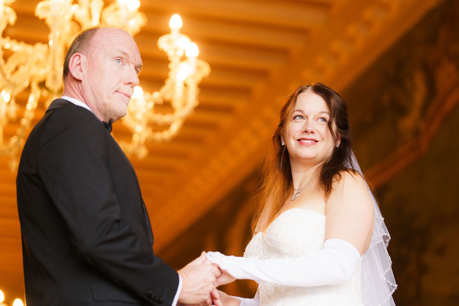 A bride and groom share a romantic dance moment under warm chandelier lighting at their wedding reception.