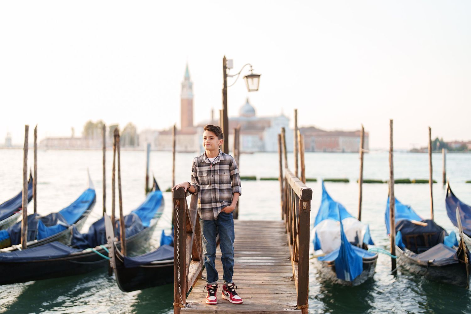 Scenic view of gondolas moored at wooden posts along Venice's Grand Canal with San Giorgio Maggiore church in background.