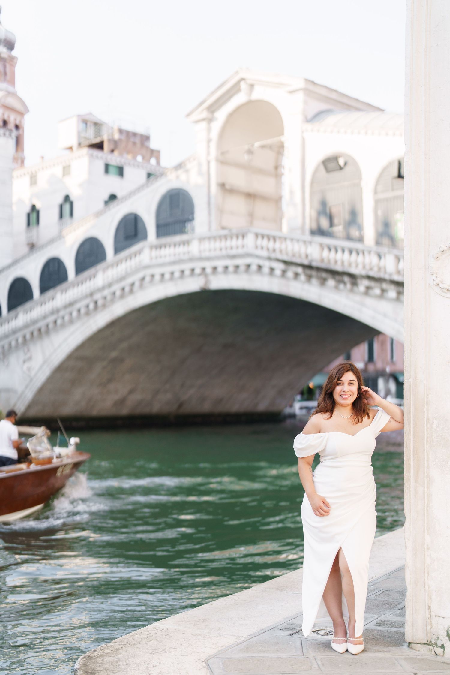 A series of romantic photos by the Rialto Bridge in Venice showing a person in a white dress near the canal.