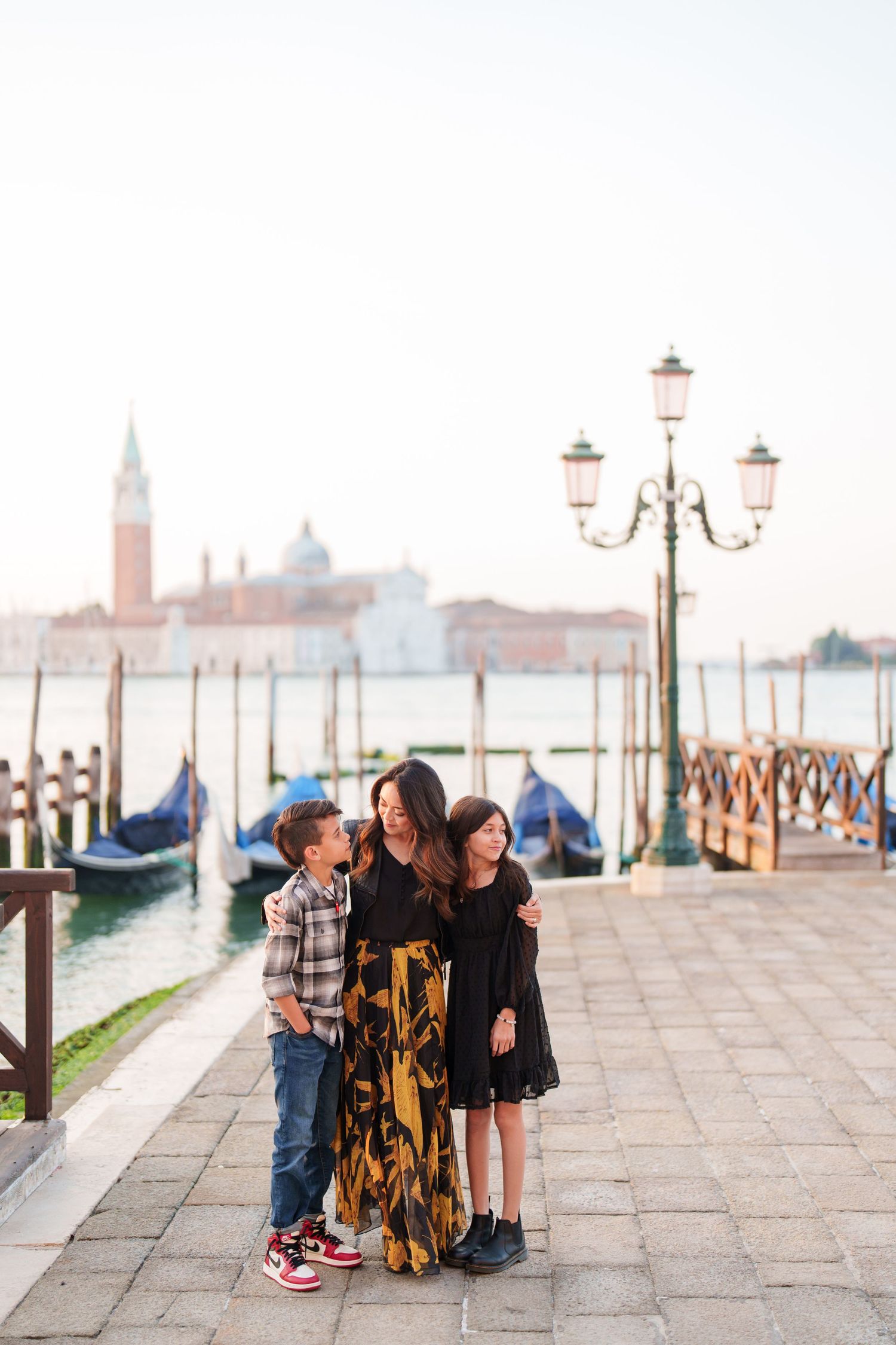 Family enjoying a scenic view of Venice's iconic skyline along the waterfront promenade at sunset.