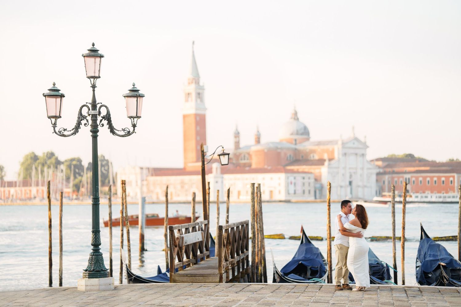 Romantic scene in Venice with gondolas and San Giorgio Maggiore church in the background during sunset.