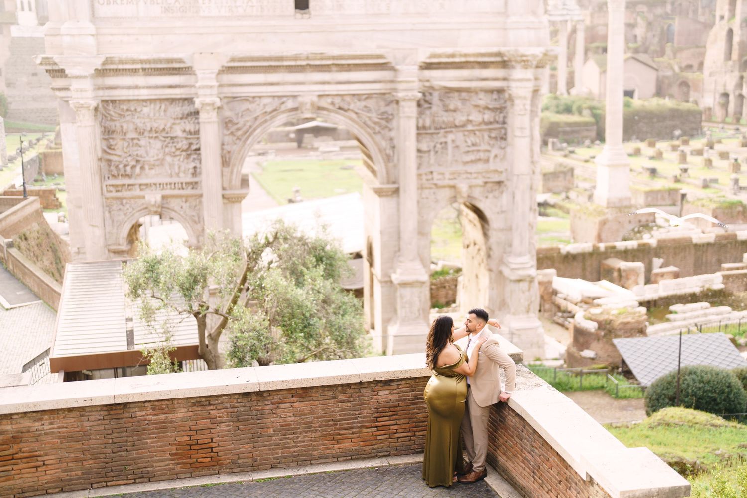 Couple embracing at the Roman Forum with ancient arches and ruins in the background in Rome, Italy.