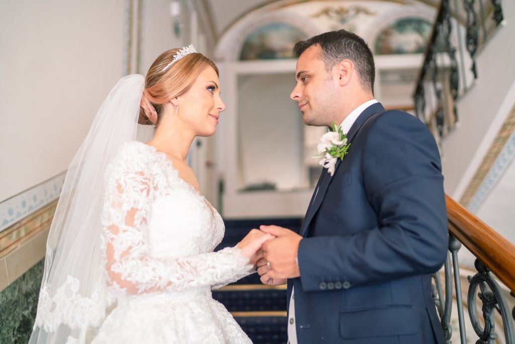Romantic wedding moment captured in an ornate interior hallway with marble details.