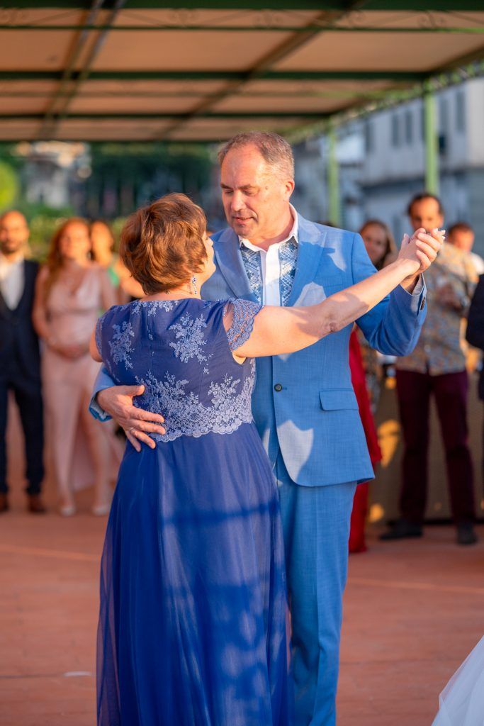 Couple in blue attire dancing together at an outdoor evening celebration.