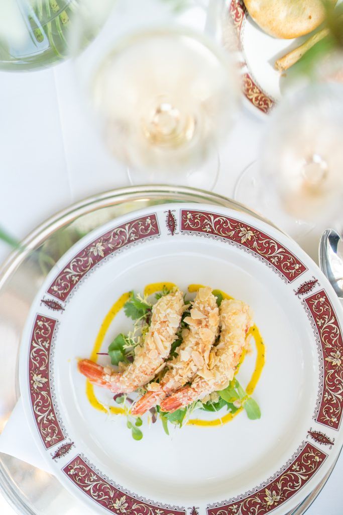 Elegant plated seafood dish with garnish on fine china with decorative burgundy border.