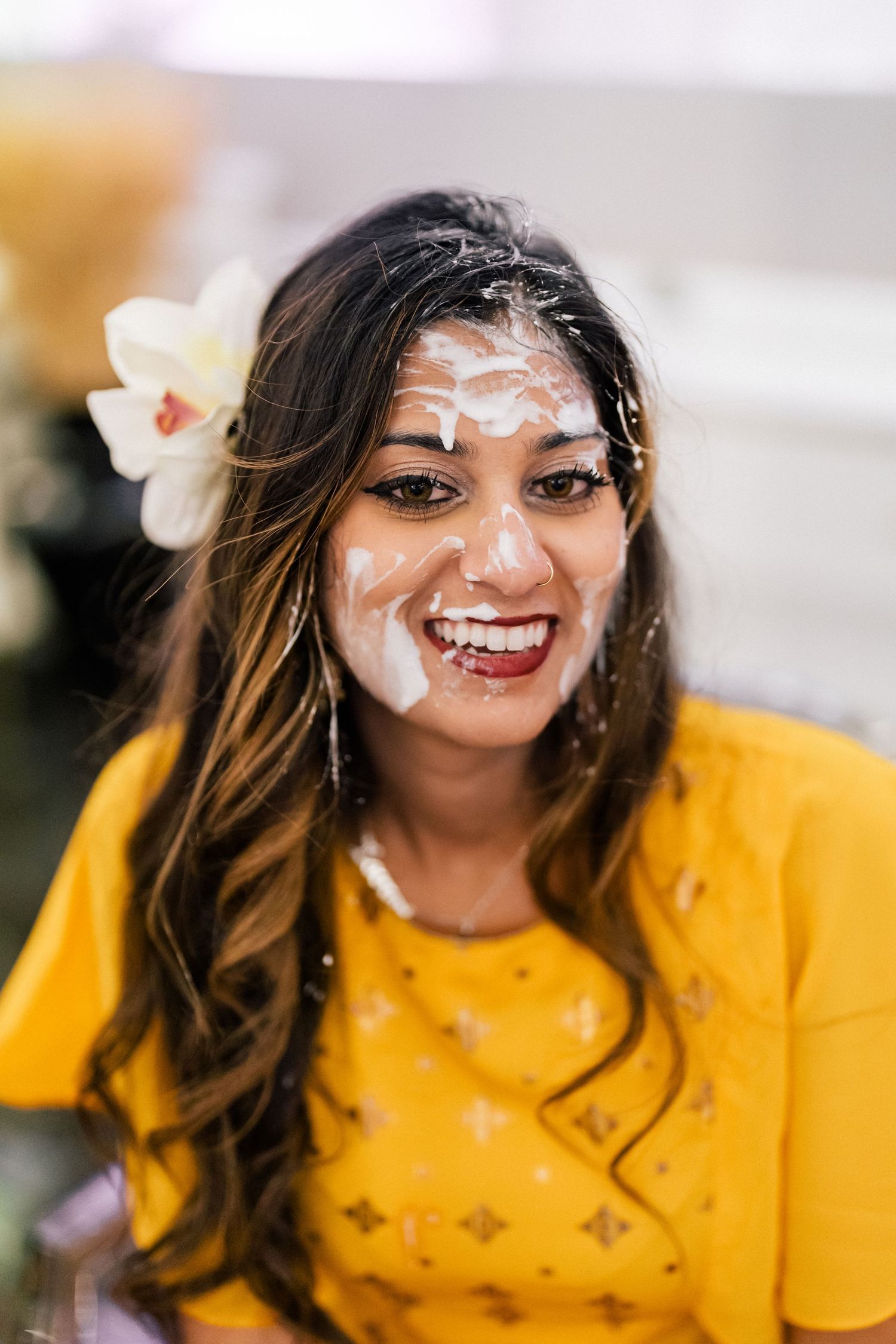 Person wearing yellow with white face paint laughing during festivities.