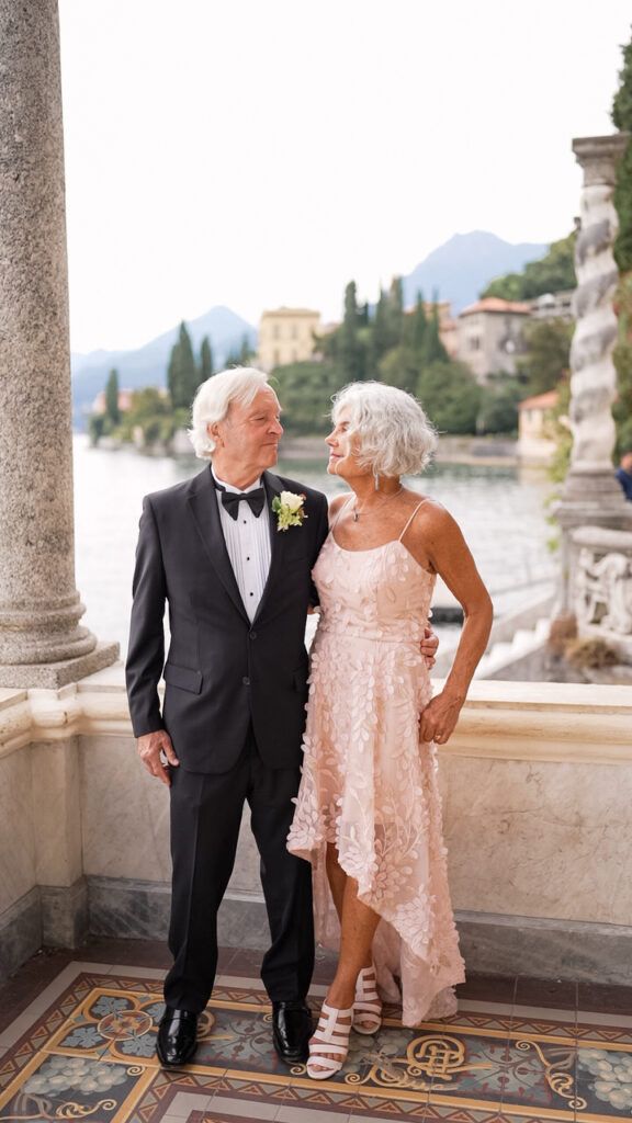Elegant couple on ornate tiled terrace with lake and mountain views in Italy.