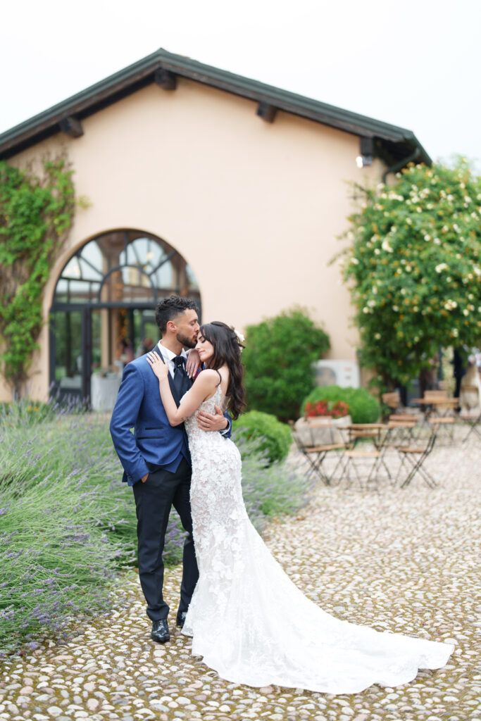 Romantic wedding portraits taken outside a beige stucco villa with arched windows.