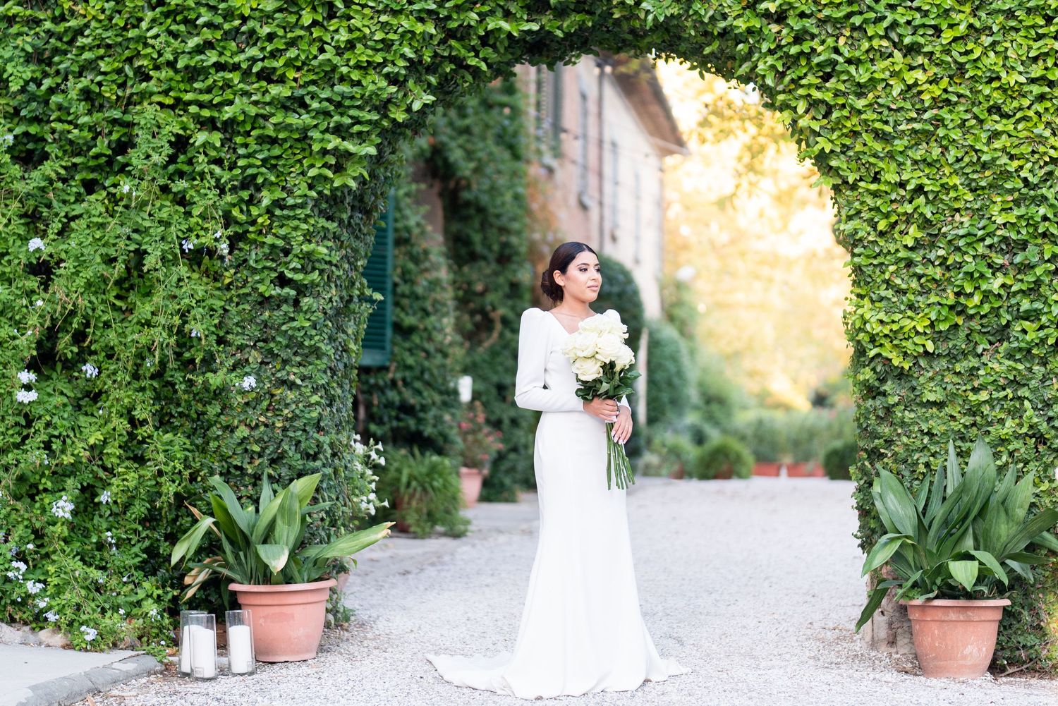 Romantic bridal portrait through ivy-covered garden archway.