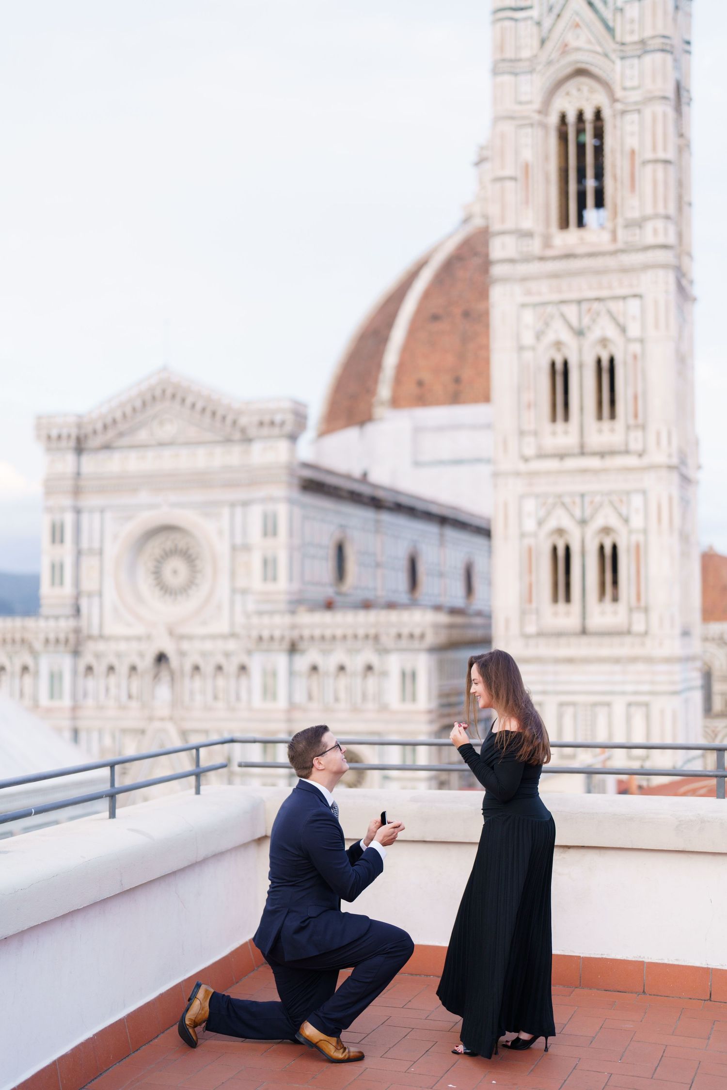 A couple shares a romantic proposal moment on a terrace overlooking the Florence Cathedral in Italy.