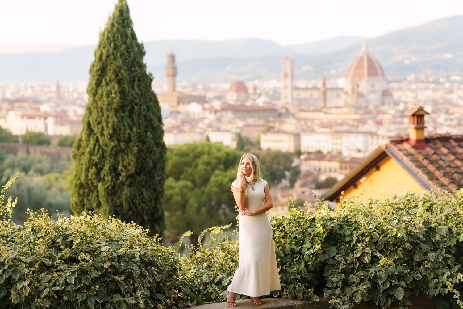 A panoramic view of Florence, Italy with cypress trees in the foreground and the iconic Duomo cathedral dome visible.