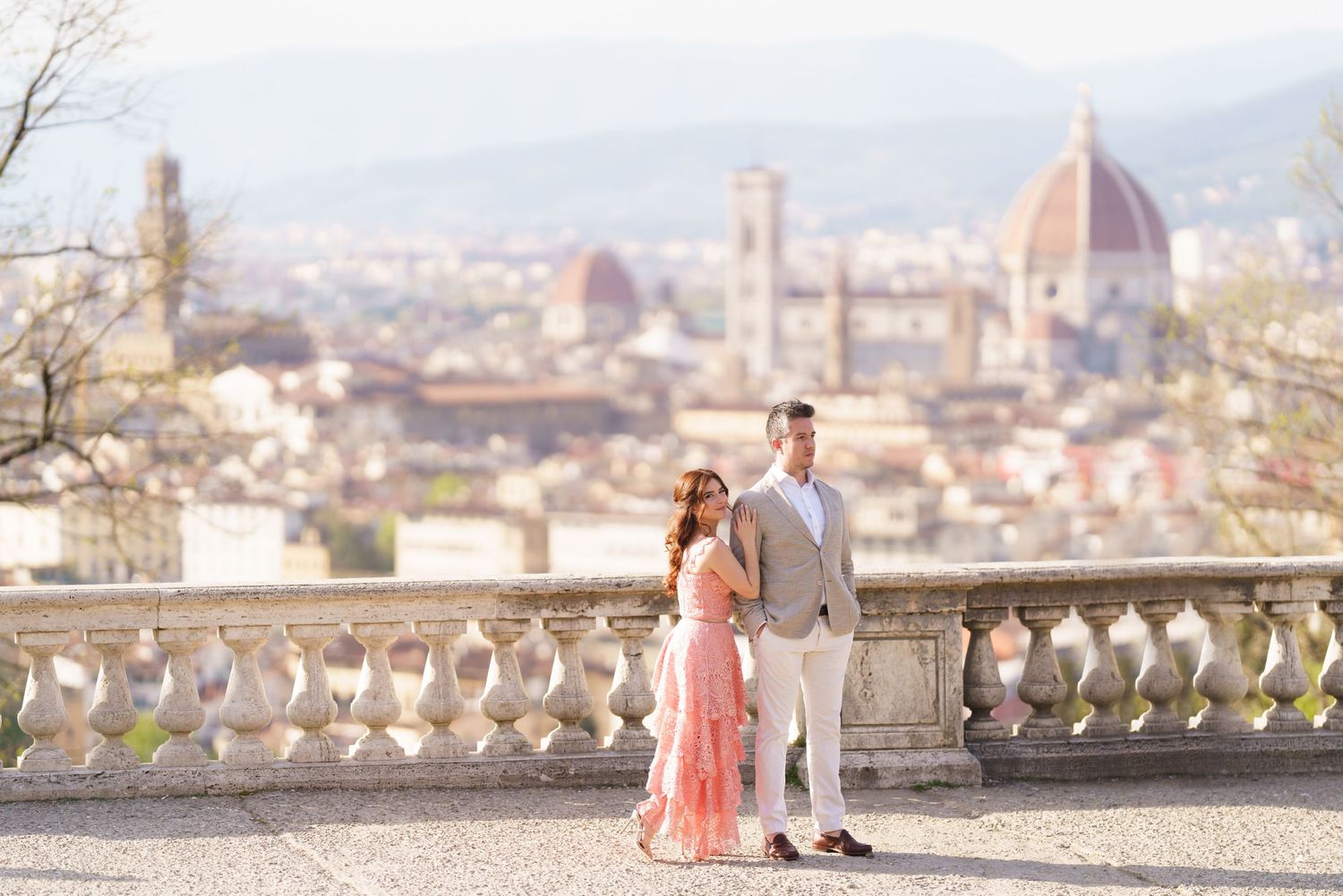 Romantic couple poses at scenic overlook of Florence, Italy with historic Duomo cathedral and cityscape in background.