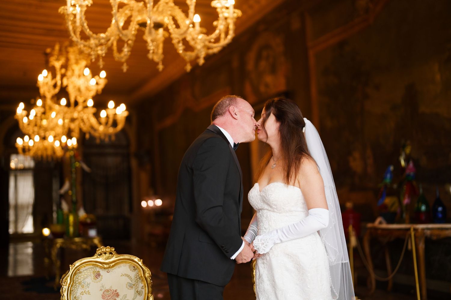A couple shares their first dance at an elegant wedding reception under glittering chandeliers.