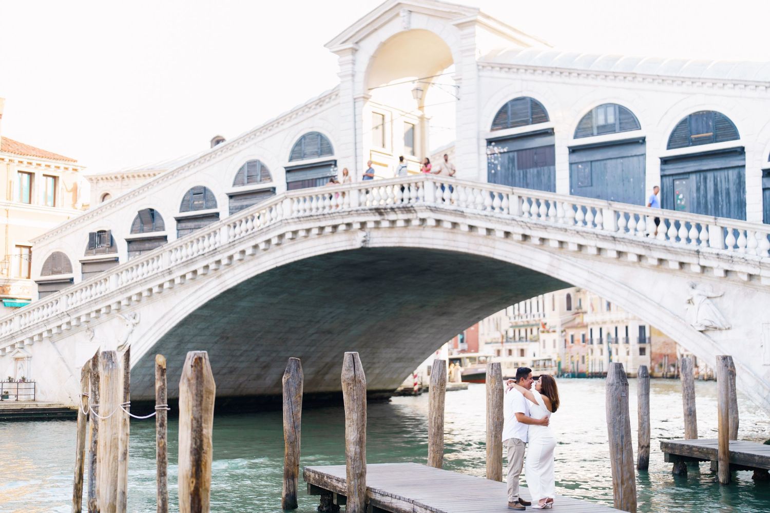 photographer venice The iconic Rialto Bridge spans across Venice's Grand Canal with its white stone arches and bustling tourists.