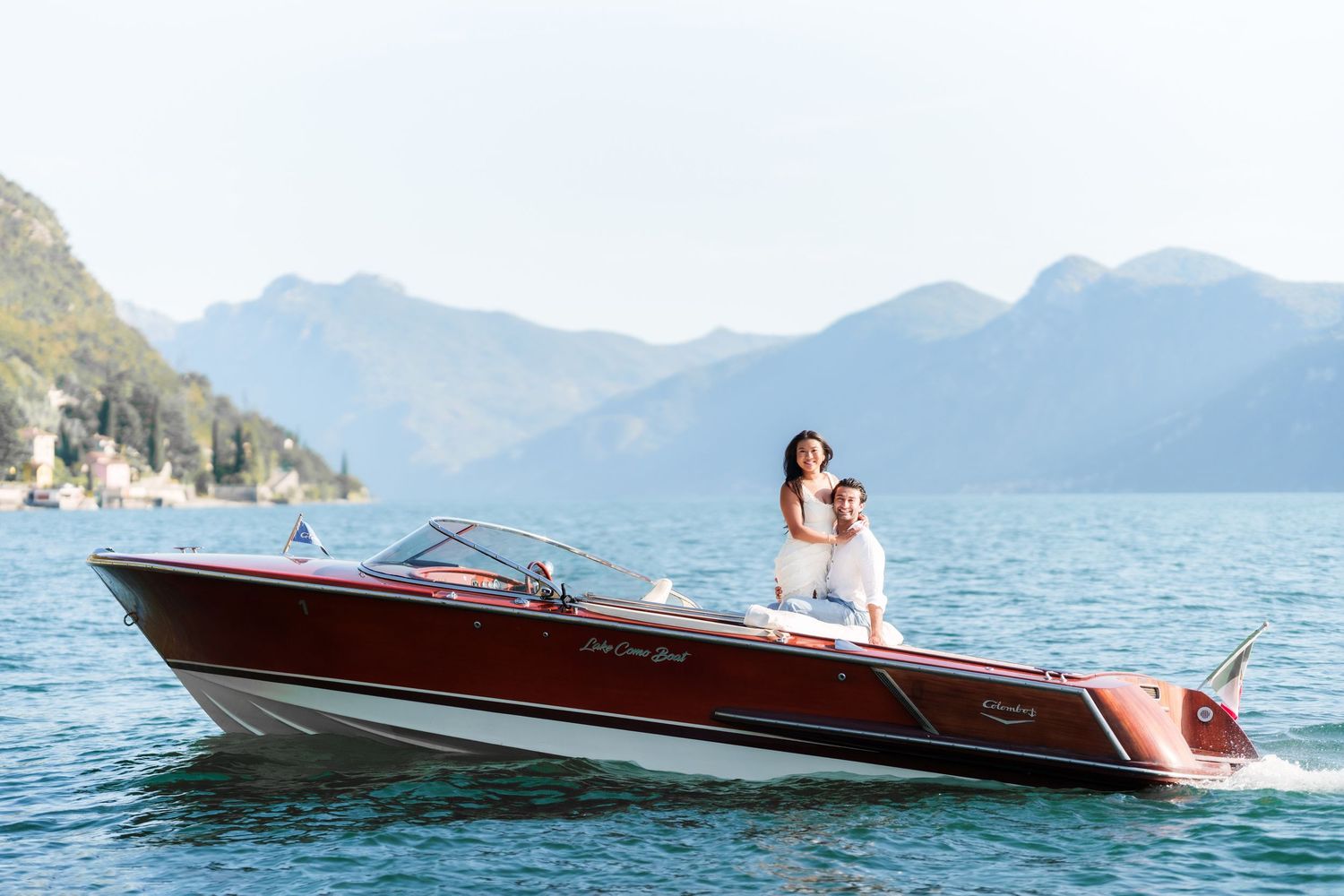 Couple enjoying a luxury Riva speedboat on Lake Como with scenic mountain backdrop.