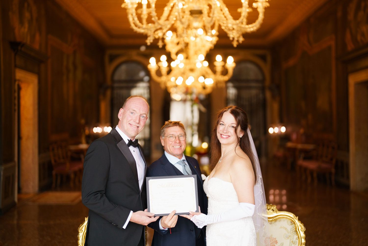 A couple shares a romantic moment under elegant chandeliers at an opulent wedding reception venue.