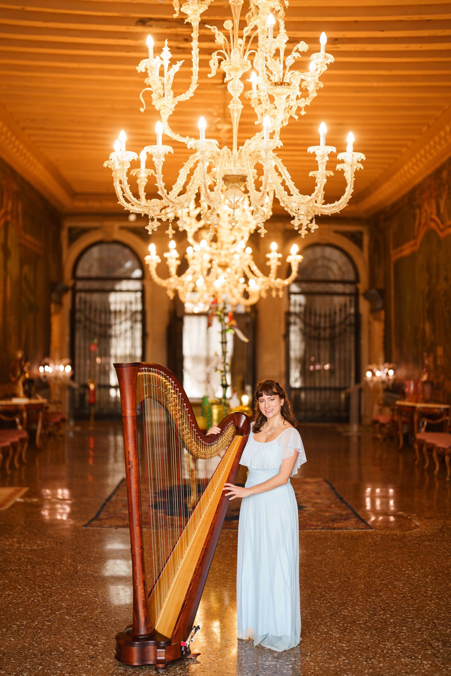 Elegant harpist performs in an ornate ballroom with crystal chandeliers and warm lighting creating a romantic ambiance.