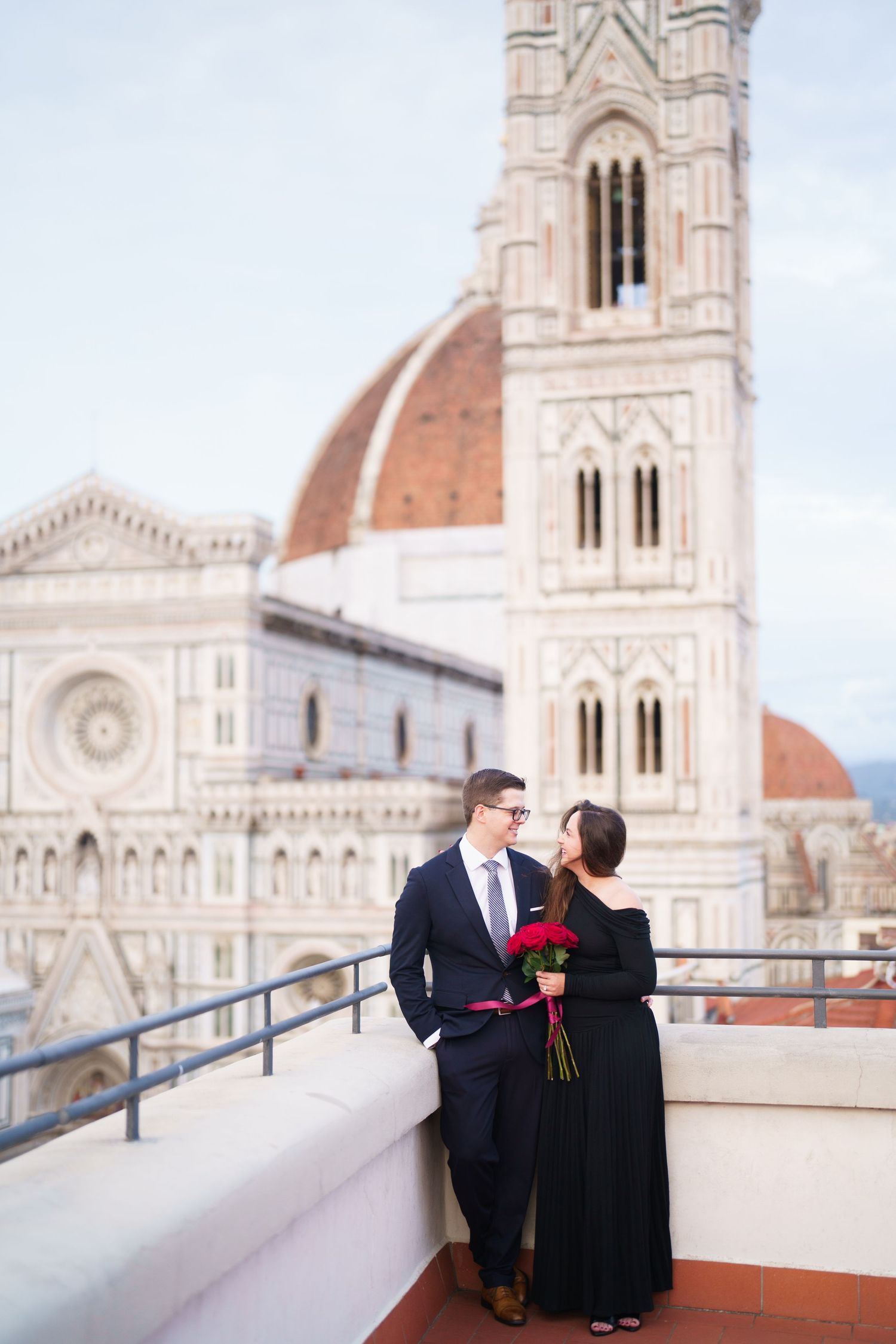 A couple stands on a terrace overlooking the historic Duomo cathedral in Florence, Italy.