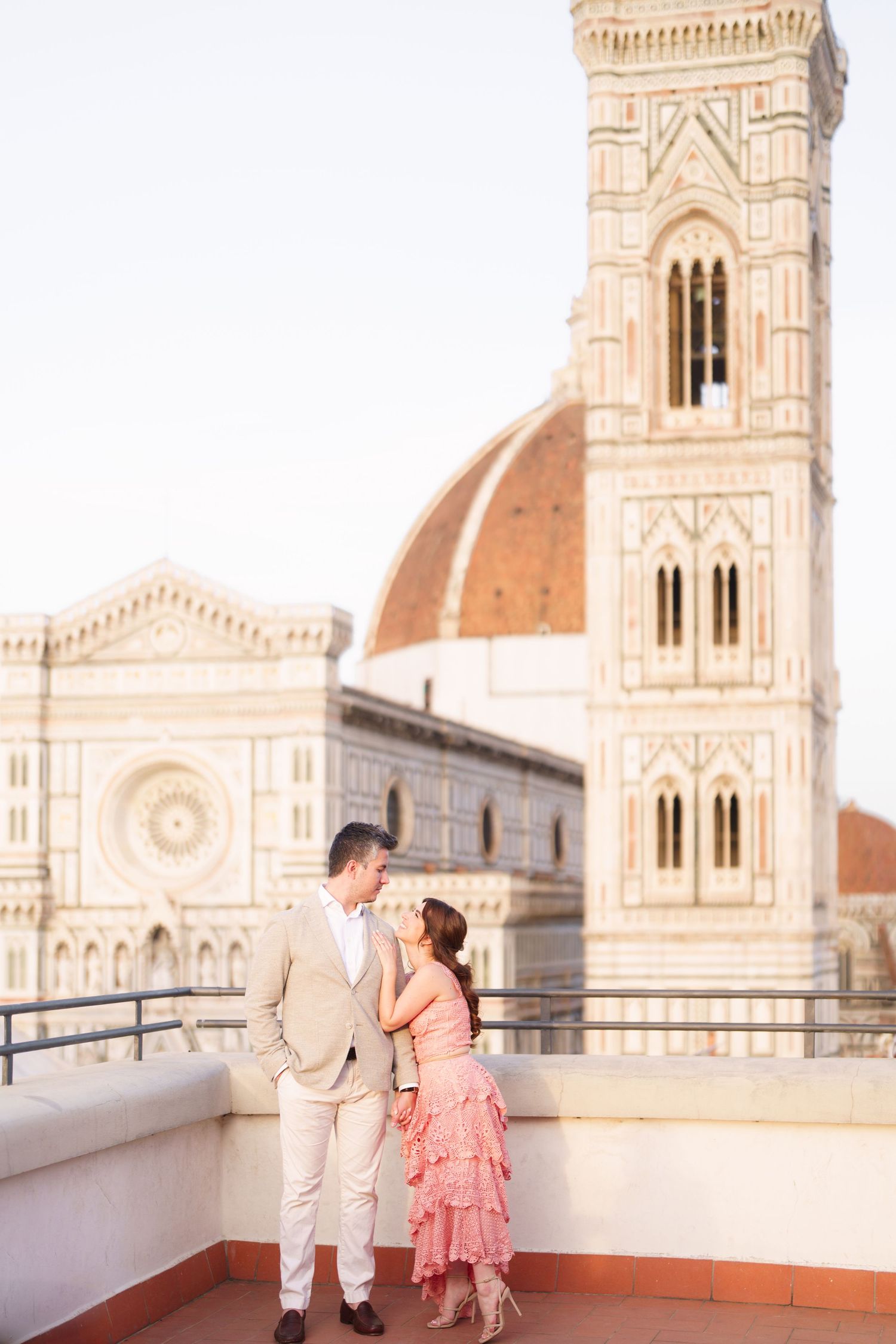 A couple shares a romantic moment on a rooftop terrace overlooking the Florence Cathedral and Duomo in Italy.