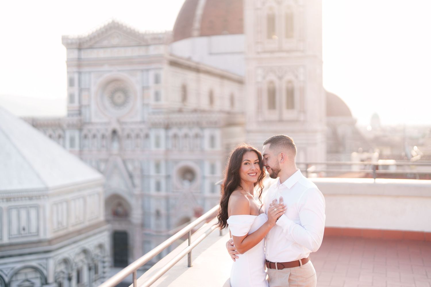 A couple in white outfits dances and poses romantically at sunset near Florence Cathedral in Italy.