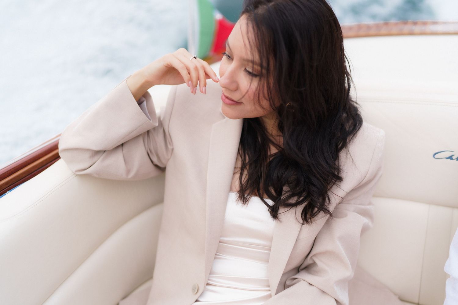 A woman in a white sweater lounges on a cream-colored couch while looking away from the camera.