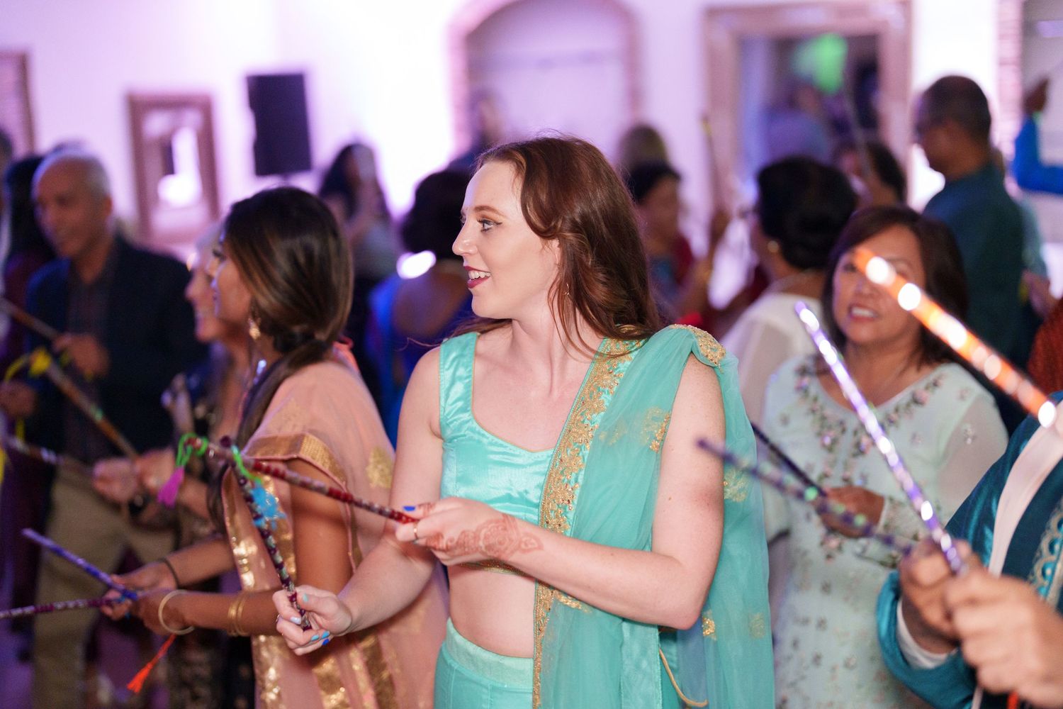 Party guests dancing with sparklers at a festive indoor celebration.