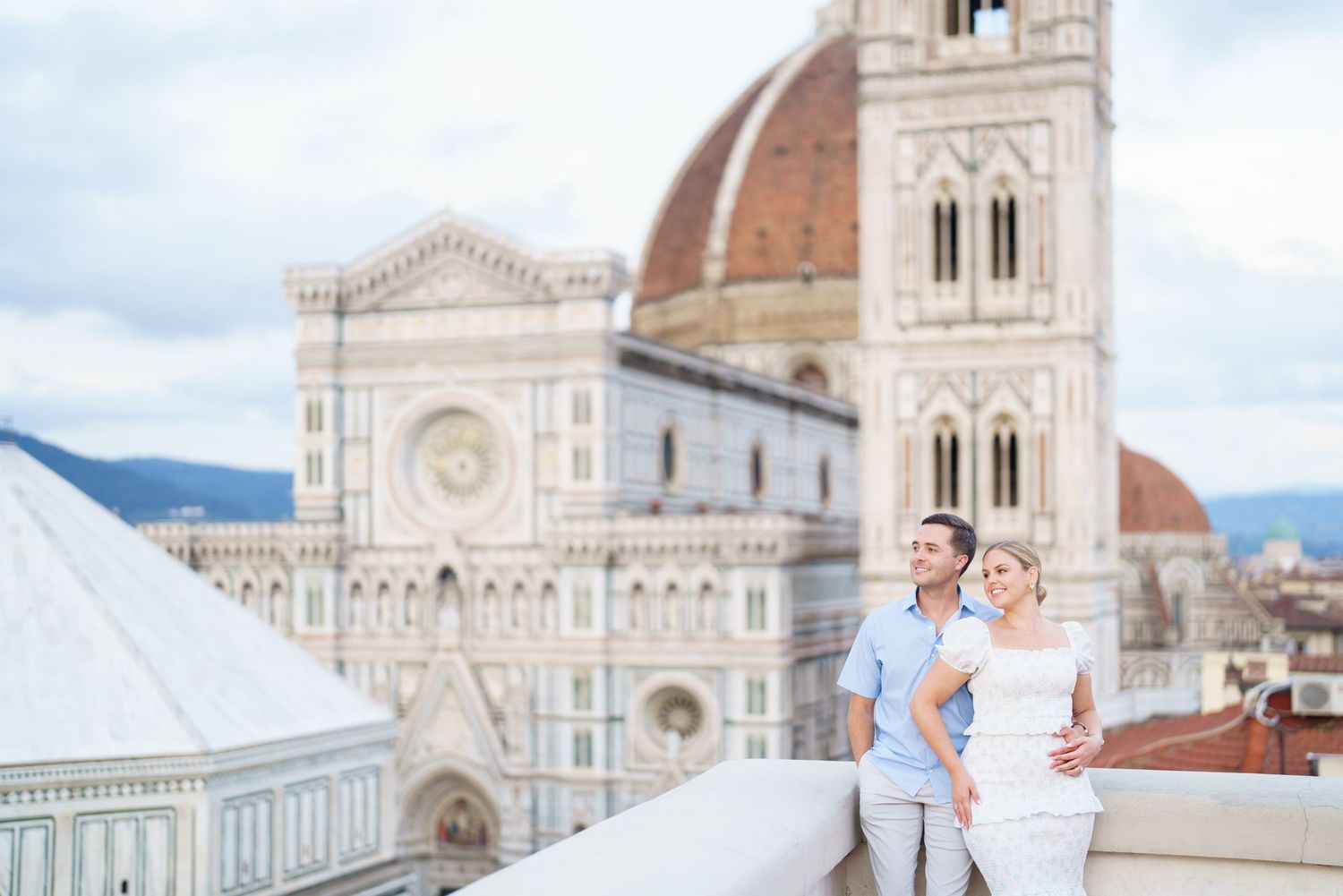 A couple in wedding attire poses in front of Florence Cathedral and Duomo in Italy on a sunny day.