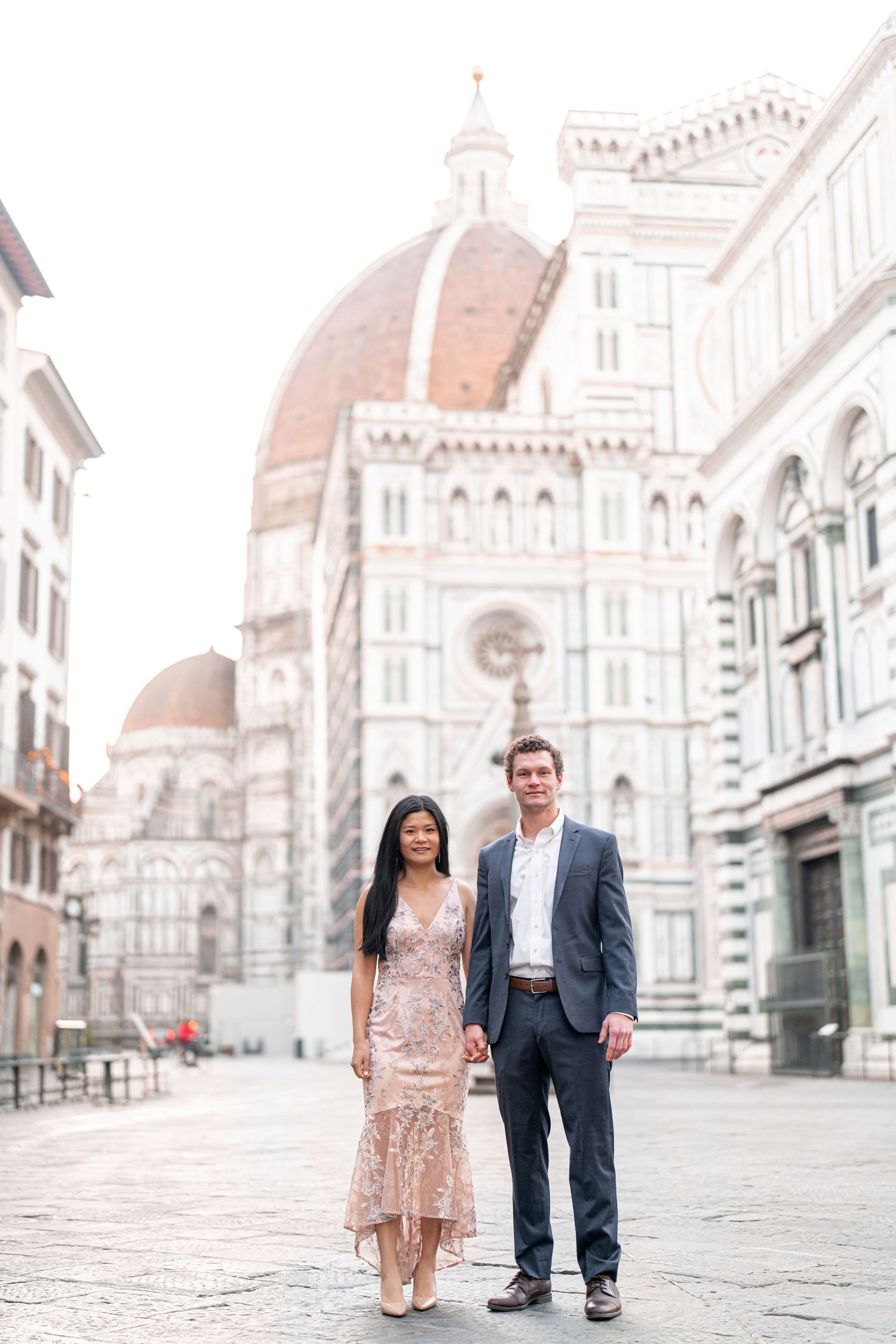 A couple in formal attire poses in front of Florence Cathedral during a romantic photoshoot in Italy.