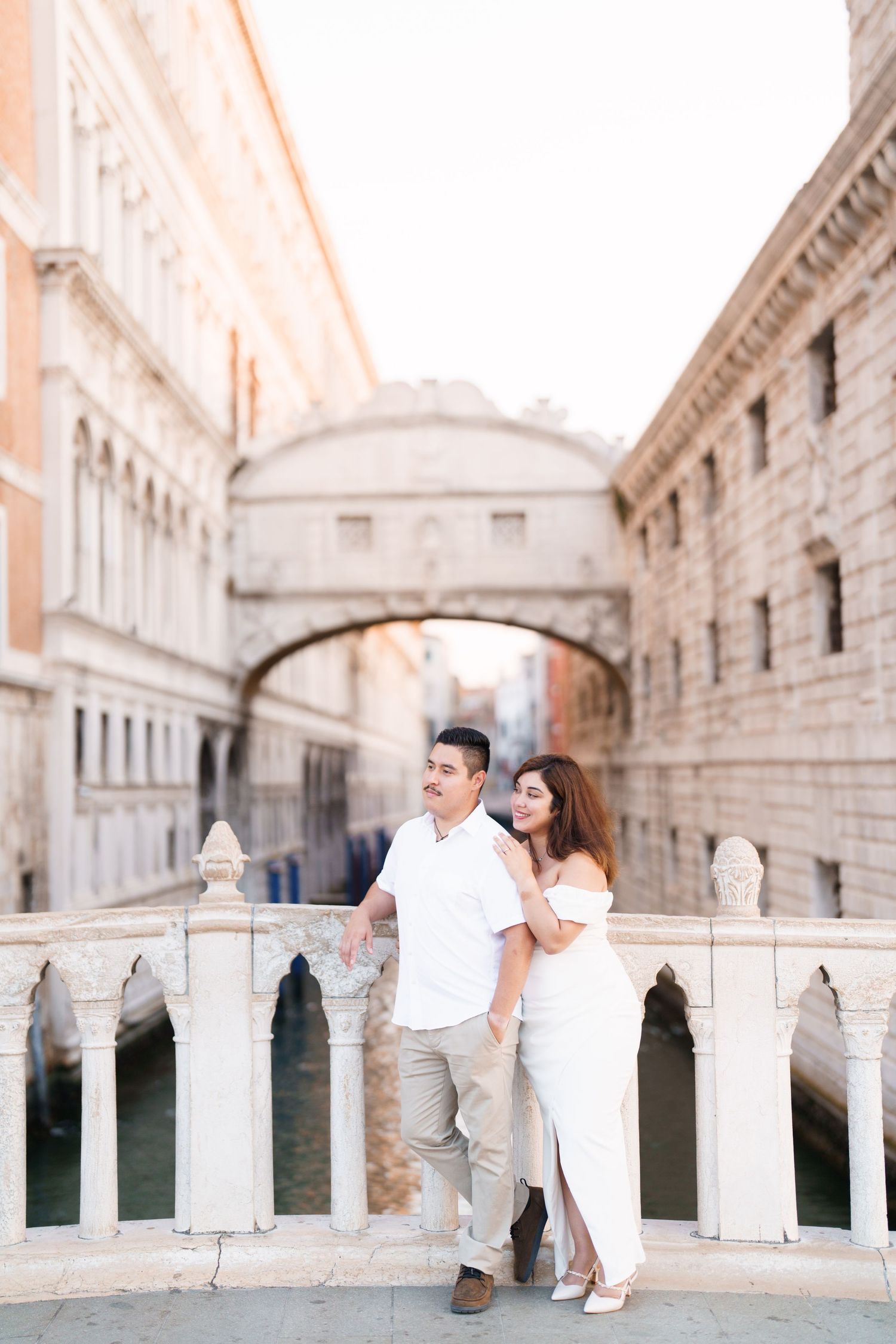A couple sits together on the ornate Bridge of Sighs in Venice, Italy during a romantic photoshoot.