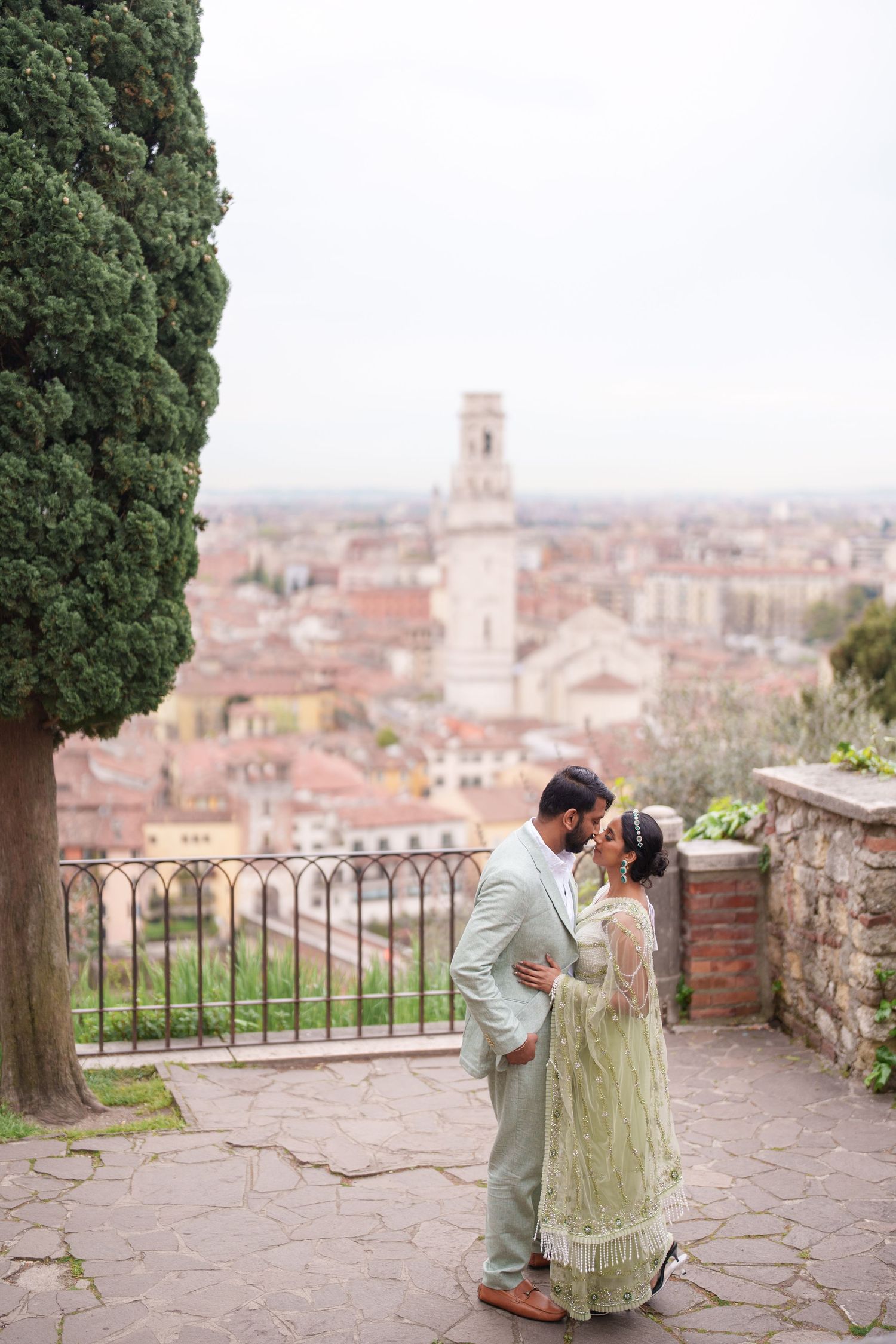 photographer veroA romantic couple embraces on a scenic terrace overlooking the terracotta rooftops and historic skyline of an Italian town.