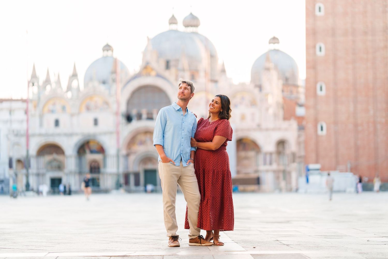 Couple standing together in St. Mark's Square, Venice, with the iconic Basilica di San Marco in the background.